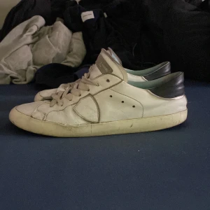 Byter gärna dessa skor mot ett par andra skor - Säljer ett par vita sneakers från phillipe model med  svarta detaljer och. Skorna har en klassisk design och är perfekta för en avslappnad stil.