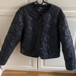 Svart Mango jacka  - Säljer en stilren svart quiltad jacka från MNG. Jackan har en rund halsringning och stängs med tryckknappar framtill. Är i bra skick och det ör bra skick. Passar också i st S. Pris kan diskuteras 