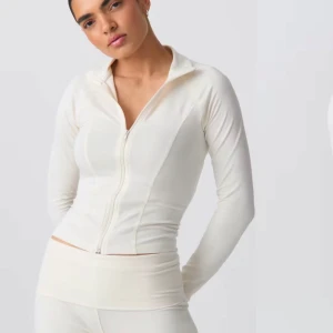 Vit långärmad tröja med dragkedja - Säljer en stilren vit långärmad tröja med dragkedja framtill. Tröjan har en tight passform och är perfekt för en sportig look. Den är tillverkad i ett mjukt och stretchigt material som ger bra rörelsefrihet.