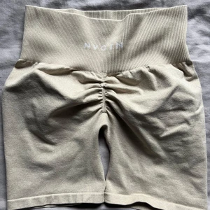 Beige shorts från NVGTN - Säljer ett par beige shorts från NVGTN med hög midja och ribbad detalj. De har en snygg rynkning back för att forma rumpan. Perfekta för träning eller en avslappnad dag. Pris kan diskuteras💓