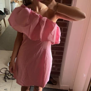 Rosa axelbandslös klänning - Säljer en söt rosa axelbandslös klänning med volangdetaljer. Perfekt för sommarens fester. Klänningen har en tight passform och är gjord i ett mjukt material.