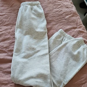 Grå mjukisbyxor från Gina Tricot - Säljer ett par bekväma grå mjukisbyxor från Gina Tricot. Byxorna har en elastisk midja och är perfekta för en avslappnad stil. De är tillverkade i ett mjukt material som gör dem sköna att bära hela dagen.