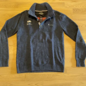 Blå tröja med brittisk flagga från Bondelid - Säljer en stilren grå tröja från Bondelid med en broderad brittisk flagga på ryggen. Mateialet är en ull blandningen och helt sjuk skön. Plagget är knoppigt men kan säkert fixas med rätt verktyg, annars helt defekt fritt🙌. Besvarar gärna frågor privat🙌