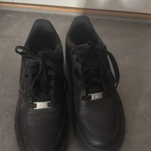 Svarta Nike Air Force sneakers - Säljer ett par klassiska svarta Nike Air Force sneakers. Skorna har inga skador eller hål. Dem är använda fåtal gånger. Dock lite smutsiga på under sidan men dem görs självklart rent innan dem skickas. För mer frågor kom privat. Köpta för 1200kr på zalando