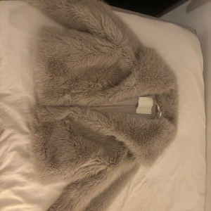 Beige pälsjacka från Vero Moda - Säljer en supermjuk och fluffig beige pälsjacka från Vero Moda. Perfekt för att hålla sig varm och stilren under kyliga dagar. Jackan har en elegant design med en slät insida och är lätt att matcha med olika outfits.