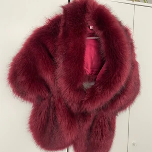 Vinröd päls - Säljer en lyxig vinröd päls med mjukt foder. Perfekt för att hålla sig varm ovanpå klänningen eller kappan. Den har en elegant design och är i nyskick! Knäpps med ett litet spänne framtill❤️