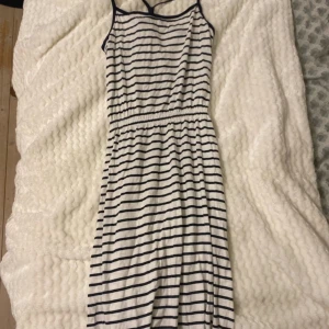 Randig klänning från H&M - Säljer en somrig randig klänning från H&M. Klänningen är ärmlös med smala axelband och har ett elastiskt band i midjan för en bekväm passform. Perfekt för varma dagar!
