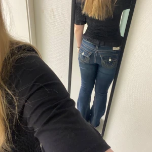 Mörkblå bootcut jeans från True Religion - Snygga mörkblå bootcut jeans från True Religion med ikonisk broderad detalj på bakfickorna. Jeansen har en låg midja och klassisk femficksdesign. Använda fåtal gånger 