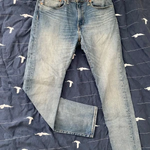Blå jeans från Levi's - Snygga blå jeans från Levi's med klassisk femficksdesign och en bekväm passform. Perfekta för en avslappnad stil. De har en traditionell knappgylf och är tillverkade i slitstarkt denim.