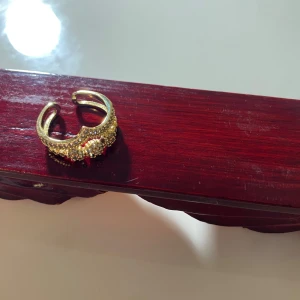 Guldfärgad ring med glittriga detaljer - Snygg guldfärgad ring med glittriga detaljer som ger en lyxig känsla. Perfekt för att ge en extra touch till din outfit. Justerbar storlek för att passa de flesta.