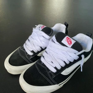 Svarta och vita Vans knu skool - Säljer ett par klassiska svarta och vita Vans sneakers med vit sula och snörning. Skorna har den ikoniska vågiga sidodetaljen och en gummisula med rutmönster för bra grepp. Perfekta för en avslappnad stil.  Nypris ca 1100