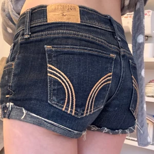 Mörkblå jeansshorts från Hollister - Snygga mörkblå jeansshorts från Hollister med klassisk femficksdesign och uppvikta kanter. Storlek W25 XS/S