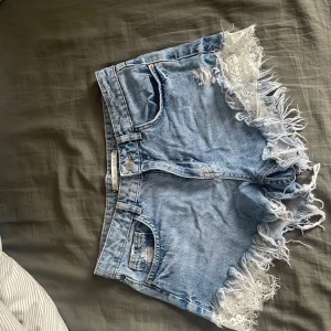 Blå jeansshorts med fransar - Säljer ett par snygga blå jeansshorts med fransiga kanter. Shortsen har en klassisk femficksdesign och en avslappnad passform. Perfekta för sommardagar!