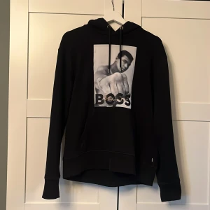 Svart hoodie från BOSS med tryck - Snygg svart hoodie med ett stort tryck på framsidan. Storlek M 