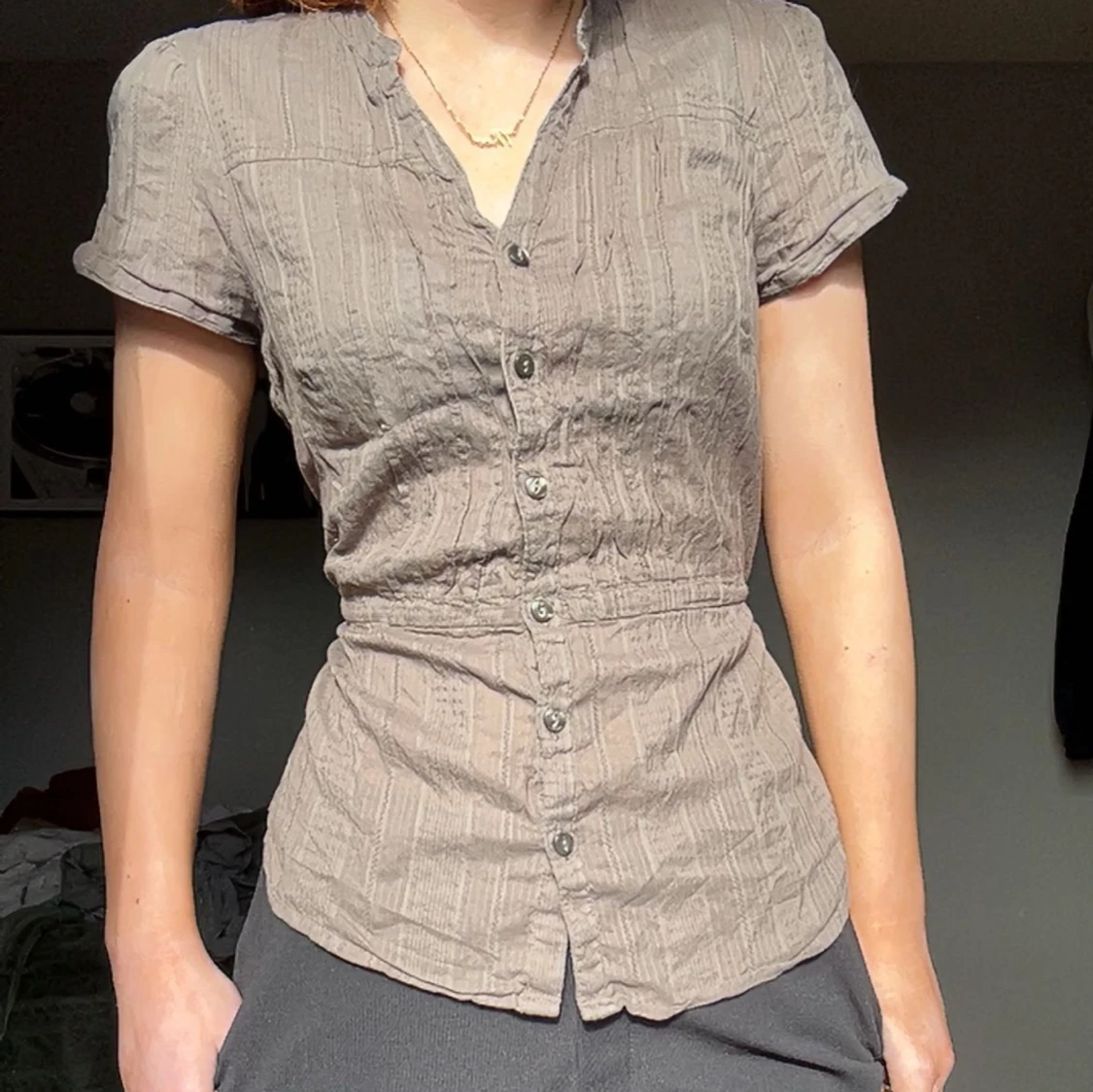 Beige/grön/grå/ kortärmad skjorta. Kan knyst på två sätt. 