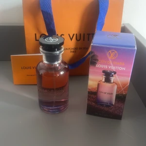 City of Stars parfym från Louis Vuitton - Exklusiv parfym 'City of Stars' från Louis Vuitton. Flaskan är elegant med en gradient av rosa och lila toner, och har en svart kork med märkets logotyp. Förpackningen har en färgglad design med en solnedgång och palmer, vilket ger en känsla av lyx och sommar.