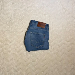 Blå jeans från Replay - Snygga blå jeans från Replay med klassisk femficksdesign och läderpatch baktill. Perfekta för en avslappnad stil.