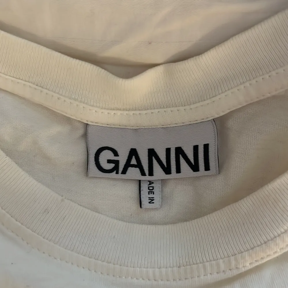 Säljer en vit t-shirt som är trekvartärmad från Ganni med tryck. Jättefin men har tyvärr aldrig kommit till användning❣️Nysprunkspris 1200kr, pris kan diskuteras!. T-paidat.