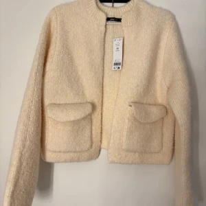 Beige stickad jacka från Gina Tricot - Säljer en mysig beige stickad jacka från Gina Tricot. Jackan har långa ärmar och två praktiska fickor framtill. Perfekt för kyliga dagar och ger en stilren look. Passar bra till både jeans och kjol. Storlek XS men är stor i storleken