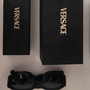 Solglasögon Versace Biggie - Svarta solglasögon från Versace. De har en gulddetalj med Versace-logotypen på sidorna. Knappt använda, bara några enstaka gånger så de är i ny skick.