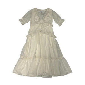 Krämvit klänning  - Krämvit klänning med volanger och trekvartsärmar. Den har en v-ringad design med knappar framtill. Aldrig använd! Perfekt till studenten eller midsommar. Kontakta vid intresse <3