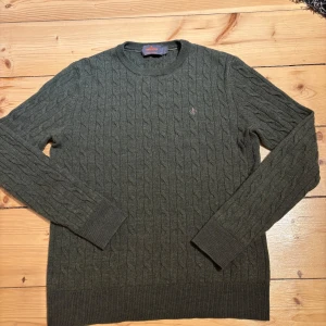 Grön kabelstickad tröja från Morris - Säljer en stilren grön kabelstickad tröja från Morris i 100% merinoull. Tröjan har en broderad detalj på bröstet. Står i storlek S men passar till xs. Är i mycket bra skick och bara används ett fåtal gånger. Hör av er vid frågar eller funderingar 