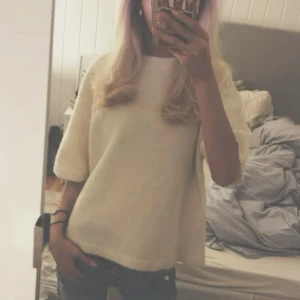 Vit stickad tröja - Säljer en stilren vit stickad tröja med korta ärmar. Perfekt för en avslappnad look. Tröjan har en rund halsringning och ribbade kanter som ger en snygg finish. Knappt använd!