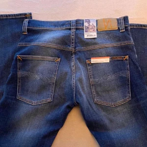Nudie jeans - Säljer ett par oanvända blå jeans från Nudie Jeans. Jeansen har en rak/slim passform och är tillverkade i ekologisk bomull. Perfekta nu inför våren med lite sköna slittningar och fades. Model är Thin Finn     W31 L30