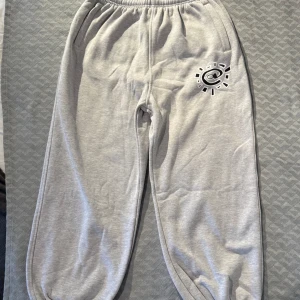 Grå ADWYSD mjukisbyxor  - Snygga grå mjukisbyxor med elastisk midja och tryck på benet samt bakficka från Always Do What You Should Do (ADWYSD). Bakfickan har dragkedja och texten 'always do what you should do'. Original tag sitter fortfarande på. Helt oanvända. Storlek: M