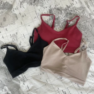 3-pack sömlösa linnen/träningstoppr med smala axelband - Tre sömlösa linnen/träningstoppar i svart, vinröd och beige med smala axelband och v-ringad hals. Mjukt stretchigt material som formar sig efter kroppen.