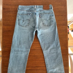Levis 501 ljusblå jeans - Klassiska Levis 501 jeans i ljusblå tvätt med raka ben. Byxorna har normal passform och är tillverkade i slitstarkt jeanstyg. Har bara använt dessa ett fåtal gånger men gillar verkligen det bekväma materialet. Tyvärr har jag vuxit ur dem.