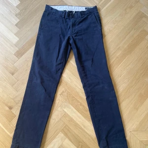 Mörkblå chinos från Polo Ralph Lauren - Säljer ett par klassiska mörkblå chinos från Polo Ralph Lauren. Byxorna har normal passform, raka ben och är tillverkade i 100% bomull. Perfekta för en stilren och avslappnad look.
