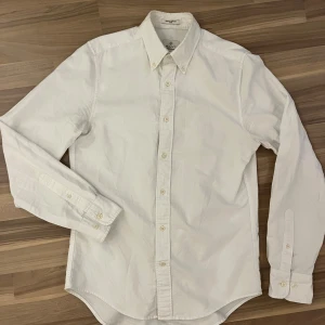 Vit oxfordskjorta från Gant - Klassisk vit oxfordskjorta från Gant med button-down krage och knappar framtill. Skjortan har lång ärm och en diskret broderad logga på bröstet. Perfekt för en clean och stilren look.