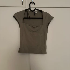 Grön topp från H&M - Säljer en gröna topp från H&M med korta ärmar och snygg v-ringning. Perfekt till jeans eller kjol för en enkel och stilren look.