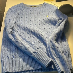 Polo ralph lauren tröja stickad - En polo Ralph lauren tröja som är stickad. Den är ljus blå men själva märket är gult. Den är använd 2-3 par ggr👍den är köpt i mall of scandinavia på kids brandstore har kvitto och påse till tröjan passar till 10-12 år👌original priser är 1100 men säljs för bara 800, pris kan diskuteras👍