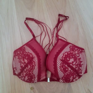 Vinröd spets-bh från Hunkemöller - Säljer en vinröd bh från Hunkemöller med vacker spets och dekorativa band framtill. Bh:n har bygel och knäppe fram, samt justerbara axelband. Materialet är polyester och elastan för en bekväm passform. Så snygg rygg. Oanvänd på grund av för liten. Jag tycker i alla fall att den satt för tight för mig med storlek 75D