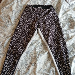 Svarta och vita prickiga träningstights från ICANIWILL - Säljer ett par snygga träningstights från ICANIWILL i storlek XS. Tightsen har svartvitt prickigt mönster, vita paneler längs benen och logga på ena benet. Tillverkade i polyester och lycra för stretch och komfort.