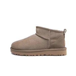 Beige UGG boots i mocka - Säljer ett par klassiska beige UGG boots i mocka med låg skaft och mjukt foder. Skorna har rund tå, platt sula och dragflik bak för enkel påtagning. Perfekta för kyliga dagar.