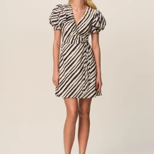 Adoore randig omlottklänning med puffärm strl 34 - Kort omlottklänning med svartvita diagonala ränder och markerad midja. Klänningen har puffiga korta ärmar och knyt i sidan. Djup v-ringning framtill och lätt a-linjeformad kjol ger en trendig siluett. Nypris: 1495kr 