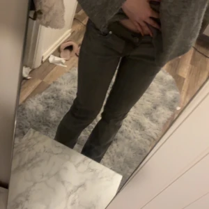 Grå jeans med broderade bakfickor - Säljer ett par lågmidjade grå jeans med snygga svarta broderier på bakfickorna och en svart patch vid linningen. Byxorna har normal passform och raka ben, med en liten bootcut, storlek i byxorna är 38 funkar för ca 170 tjej💕💕
