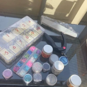 Nagelkit med glitter och tillbehör - Ett komplett nagelkit med olika burkar glitter i flera färger, en ask med lösnaglar i olika storlekar, nagelfil, nagelklippare och glitter formade som fjärilar. Perfekt för att skapa kreativa nageldesigner hemma.🦋 ej använt!!
