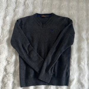 Morris tröja - Säljer en mörkgrå v-ringad tröja från Morris med en blå broderad logga på bröstet. 100% merinoull . Bra skick förutom att lappen är lite trasig se bild 3. Storlek L sitter dom xs, hör av er vid frågor