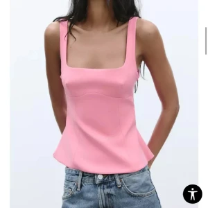 Rosa linnetopp med rosett i ryggen - Säljer en söt rosa linnetopp med fyrkantig urringning och breda axelband. Toppen har en stor rosett och öppen rygg, vilket ger en unik och trendig look. Perfekt att matcha med jeans eller kjol. Väldigt liten i storlek