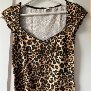 Leopardmönstrad topp från Nelly - Säljer en snygg leopardmönstrad topp från Nelly i storlek XS. Toppen har v-ringning med svart spetskant och korta ärmar. Perfekt för dig som vill sticka ut med ett djurmönster! Aldrig använt💕