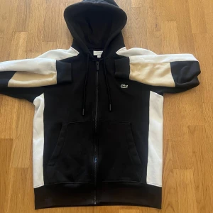 Lacoste kofta  - Fin Lacoste kofta som är i bra skick. Koftan är köpt från Zalando för 1200 kronor. Priset är hugget i sten vilket betyder att det ej går att diskuteras. OBS!! Produkten har tappat lite färg så att ni ej klagar senare.