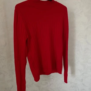 Röd ribbad tröja från NA-KD - Säljer en snygg röd polotröja från NA-KD i storlek S. Tröjan är ribbad och har långa ärmar samt en hög hals. 