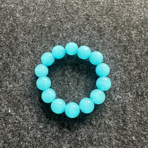 Turkost pärlarmband - Säljer ett snyggt armband med stora, runda pärlor i en klar turkos färg. Armbandet är elastiskt och passar de flesta handleder. Perfekt för att ge din outfit en färgklick!