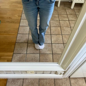 Ljusblå bootcut jeans med fickdetaljer - Säljer ett par ljusblå jeans med bootcut passform och snygga fickdetaljer bak. Jeansen har normal passning och klassisk femficksdesign. Perfekta för dig som gillar en tidlös och avslappnad stil.