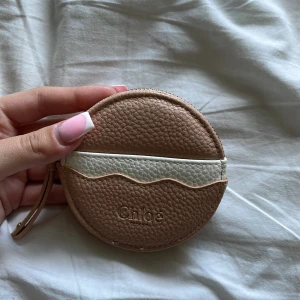 Rund plånbok från Chloé i beige och vitt - Superfin rund plånbok från Chloé i beige skinn med vit vågig detalj. Praktisk och perfekt att ha med något litet eller t.ex pengar💗