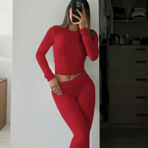 Röda tighta mjukisbyxor med tröja - Säljer ett par röda tighta mjukisbyxor med hög midja. Byxorna har en enkel design utan synliga detaljer och är gjorda i ett stretchigt material som sitter skönt mot kroppen. Perfekta för en avslappnad och sportig stil. Även tröjan följer med :)